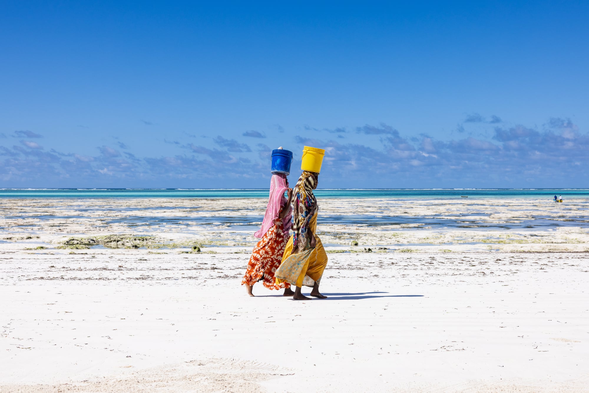 Two women walking the beach past Matlai with their octopus catch in buckets carried on their heads