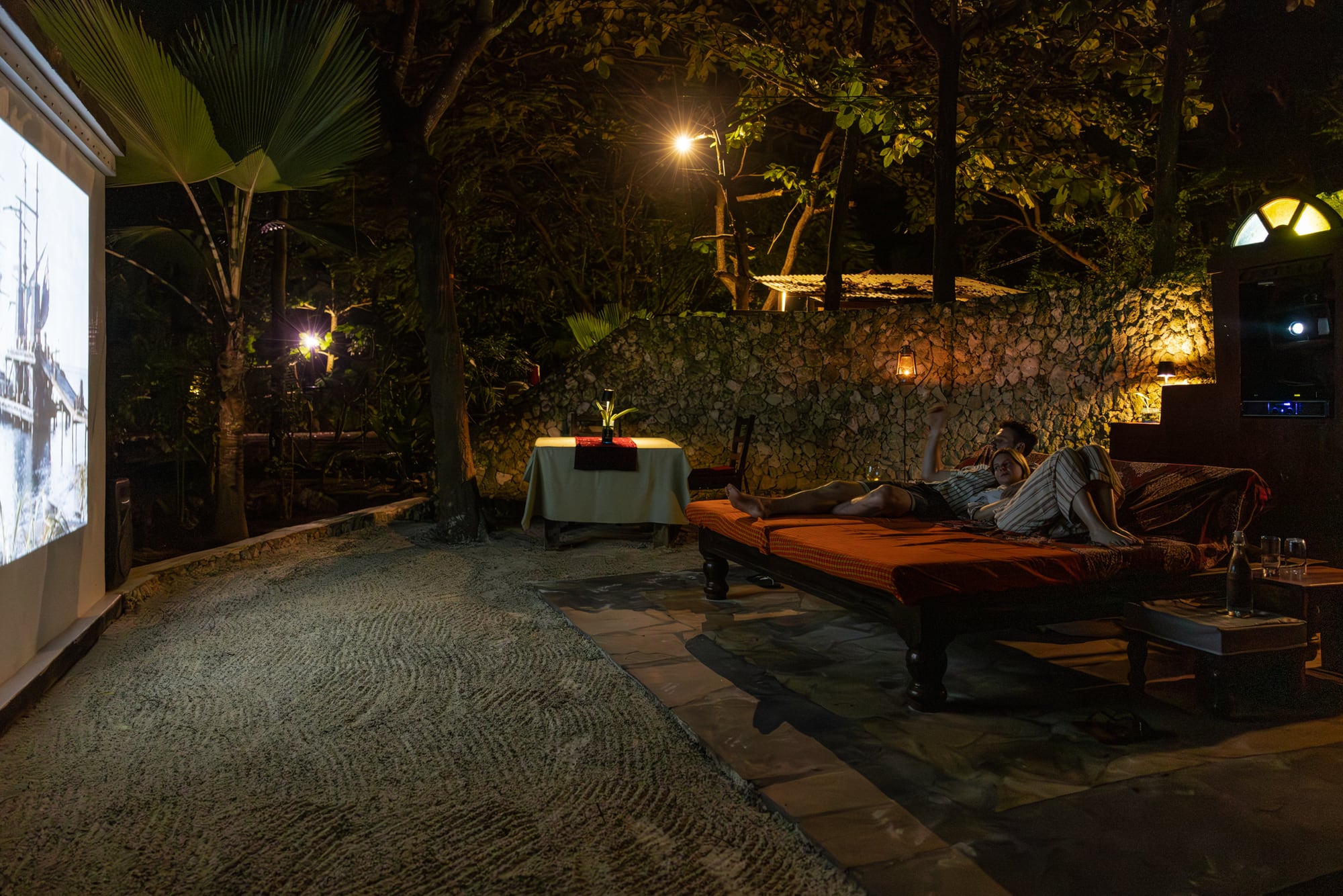 A film projected in the garden after dark, watched from a daybed.