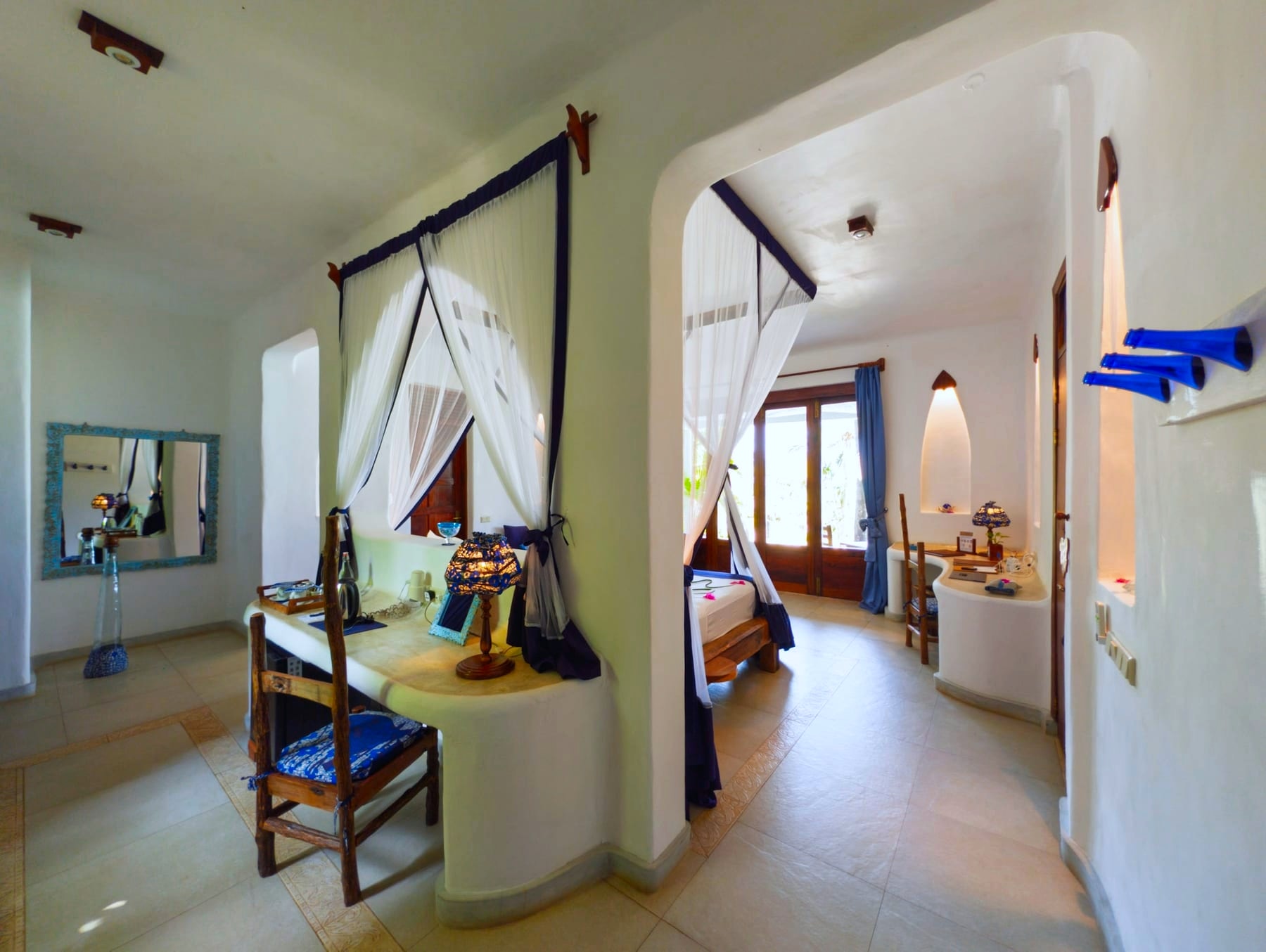 Wnętrze pokoju Maji w Asili House, Boutique Hotel Matlai na Zanzibarze, z ręcznie wykonanym wystrojem, w tym uchwytami na ręczniki z niebieskich butelek i świecami z recyklingowanego oleju.