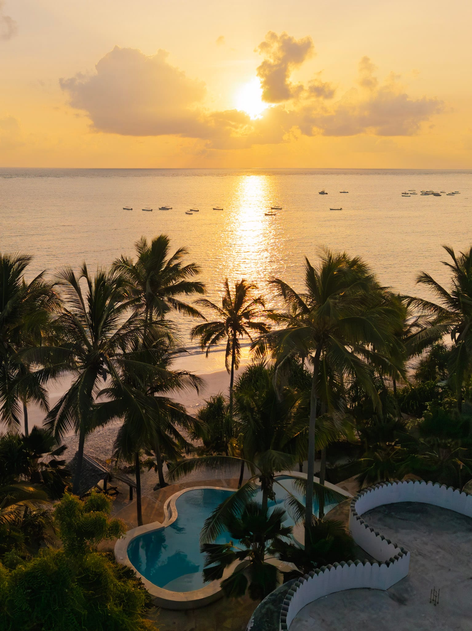 Lever du soleil sur la mer, vu d’en haut, au-dessus des palmiers et d’une piscine