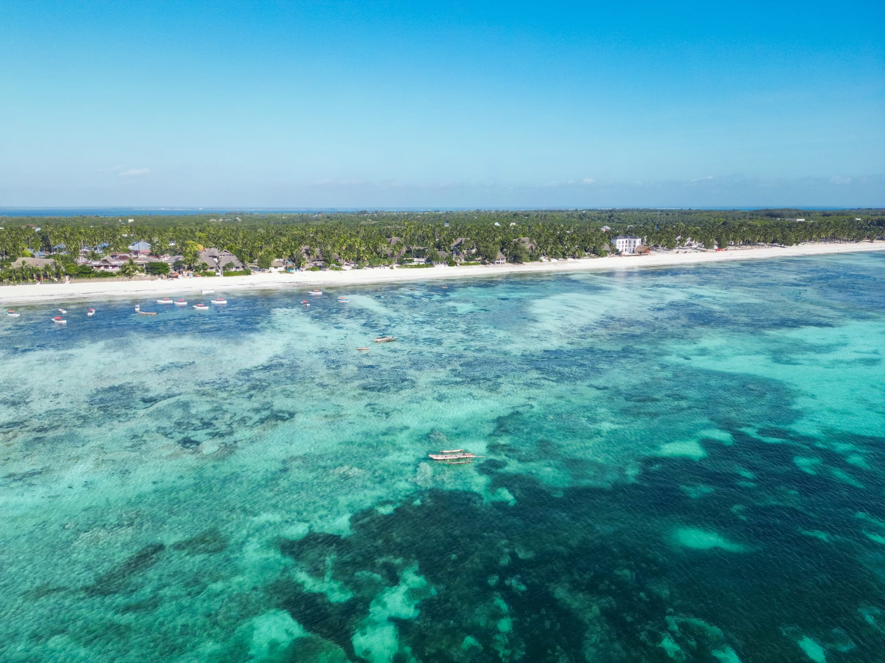 Aerial view of Zanzibar's coastline with clear turquoise waters, white sand beach and palm trees