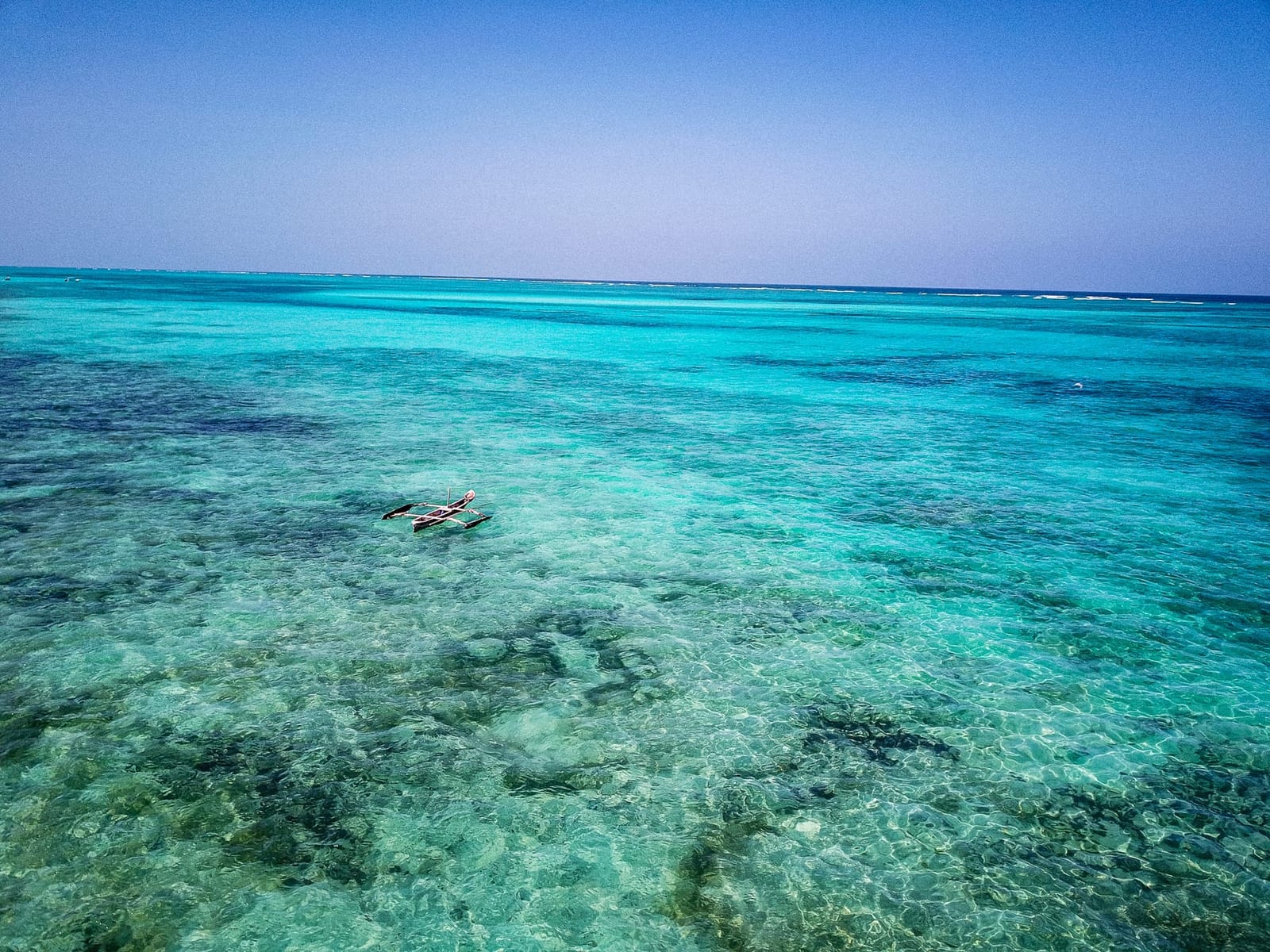Vista aerea di una tradizionale barca da pesca in legno su acque turchesi limpide al largo di Michamvi Pingwe