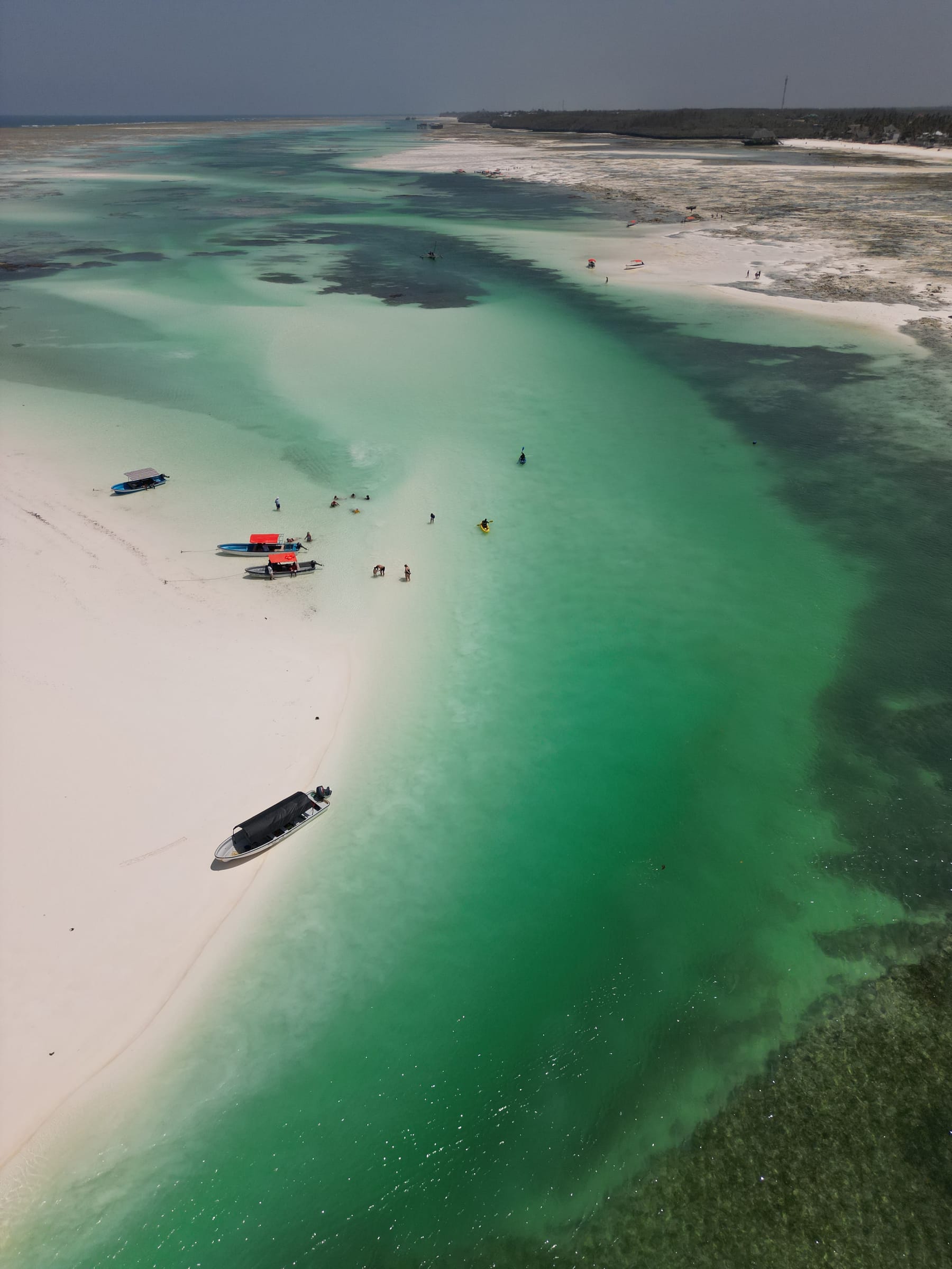 Boats anchored off a sandbank in turquoise water, seen from the air