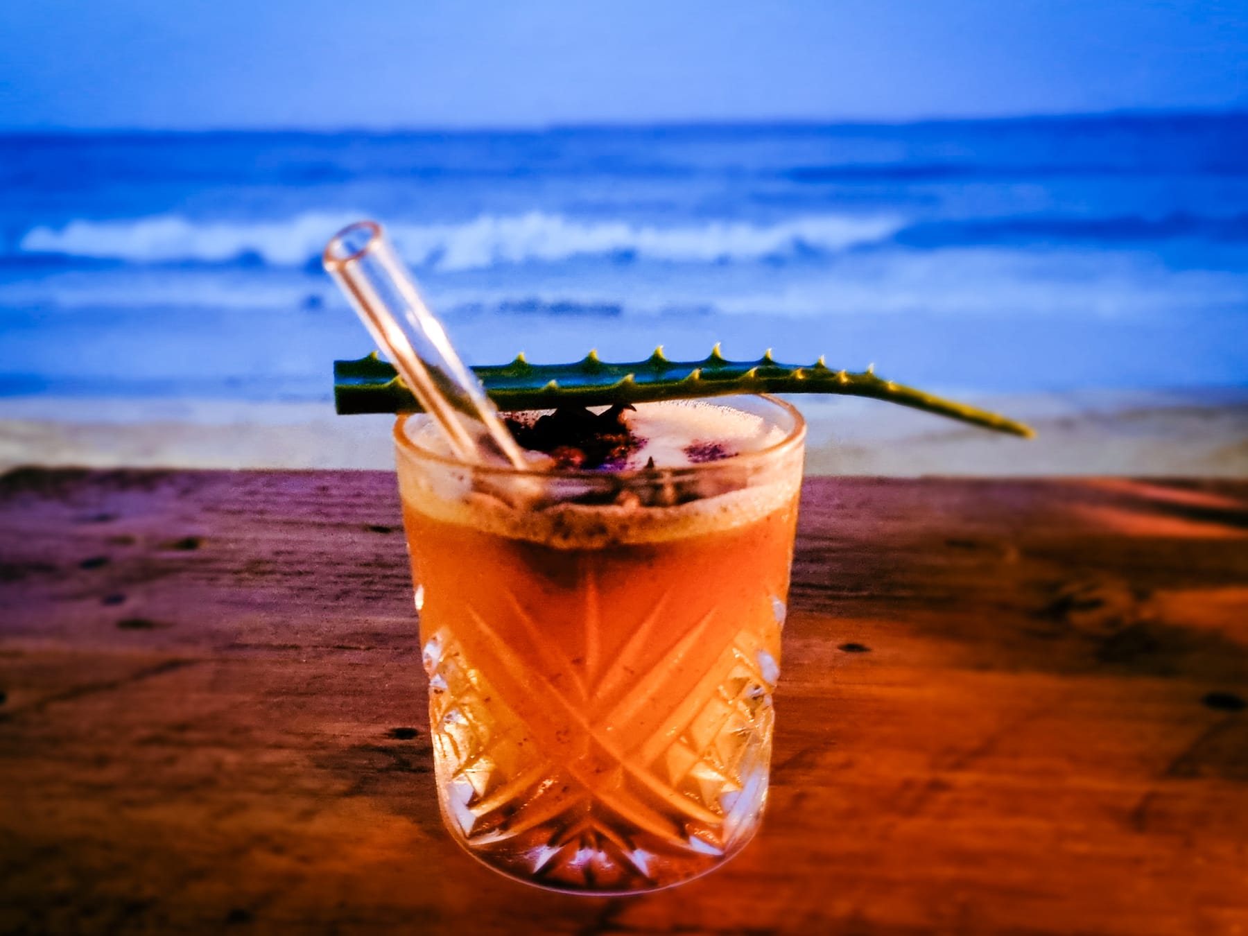 A cocktail on a table at Zatiny, the ocean behind it.