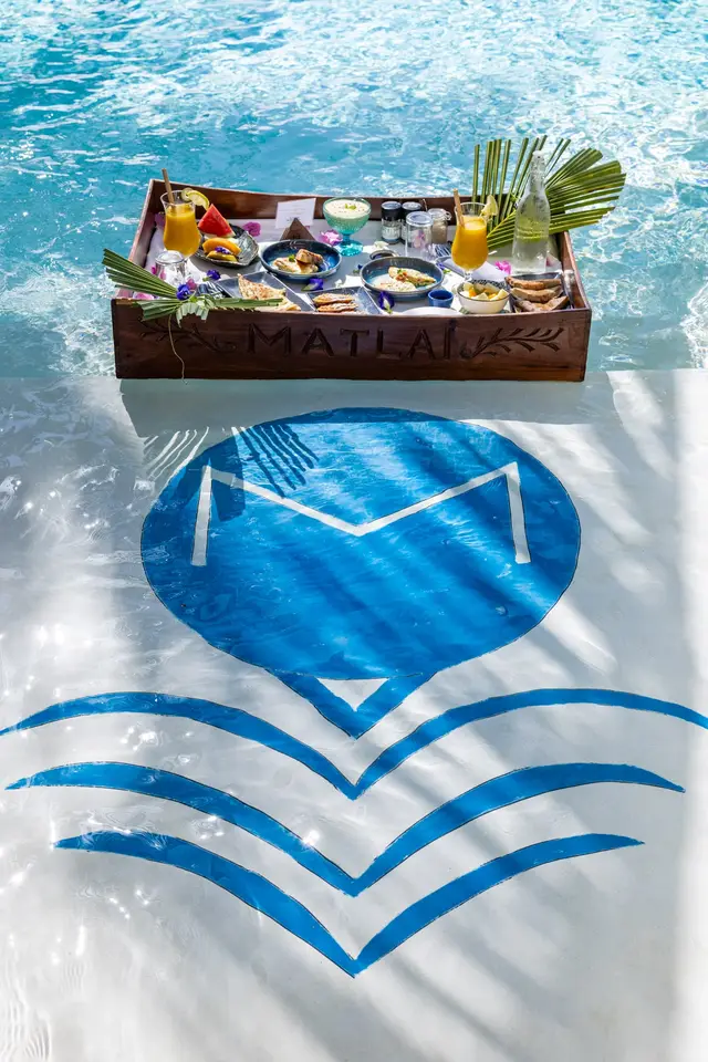 A breakfast tray on the pool water above the blue Matlai emblem on the pool floor