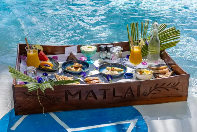 A floating breakfast tray with juice, fruit and small dishes on the water of the Villa Kidosho pool
