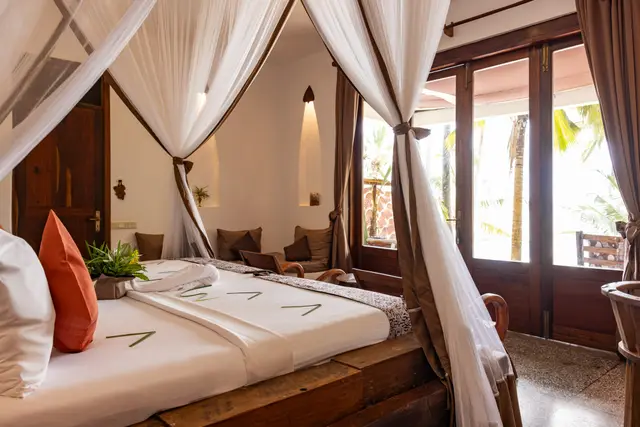 The Dunia room seen from the foot of the bed, with white nets and wooden balcony doors