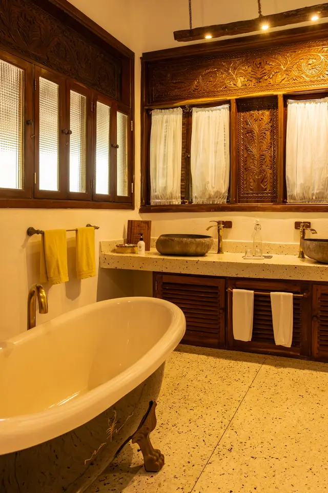 The Hewa bathroom with a freestanding bathtub, a double washbasin and warm lighting