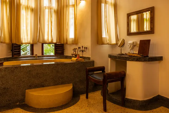 The Jua bathroom: a deep bath set below tall windows with curtains drawn back