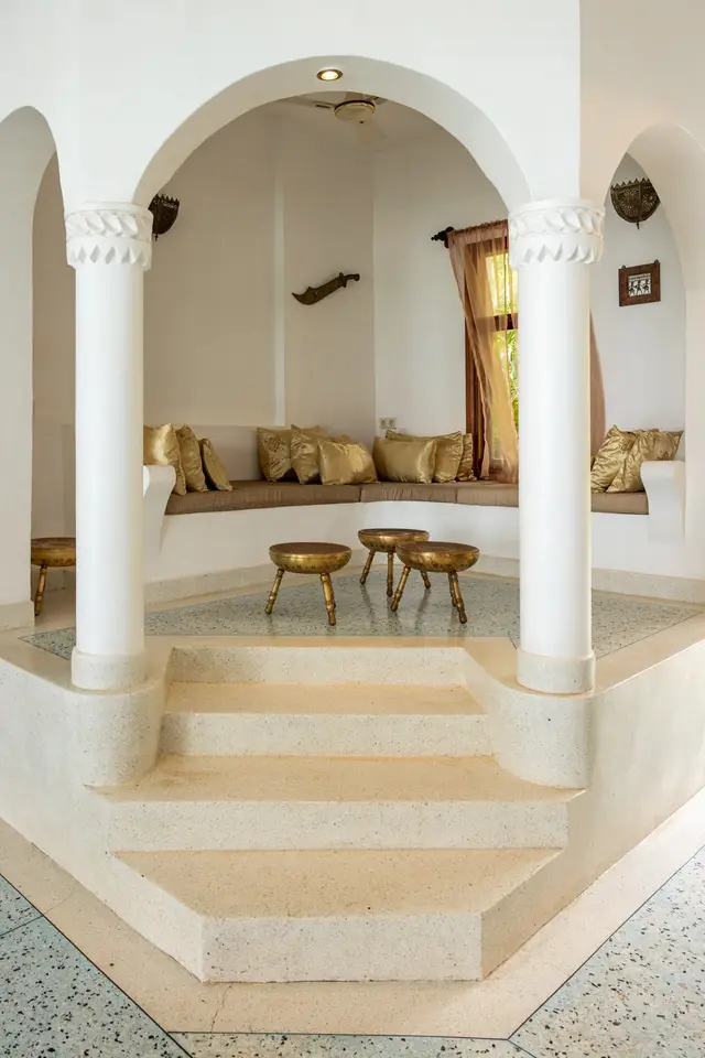 The shared baraza lounge of Villa Kidosho: white arches and columns, steps and a seating area at the back
