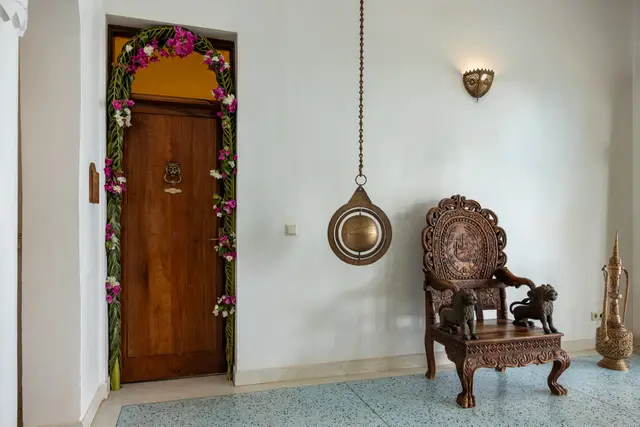 A wooden door framed with flowers in the main lounge of Villa Kidosho, with a carved chair beside it