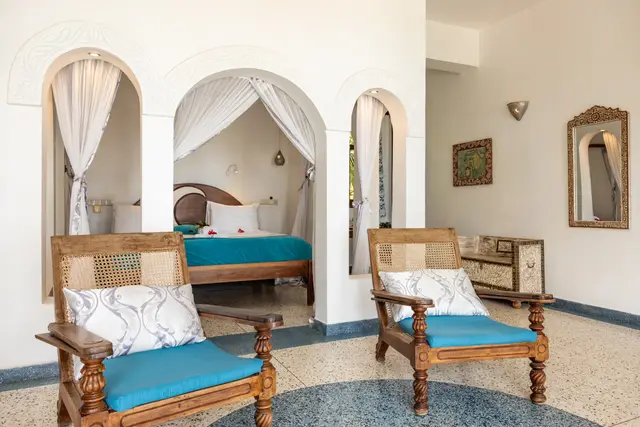 Two wooden chairs with turquoise cushions in the Mwezi suite, with arched alcoves and a terrazzo floor