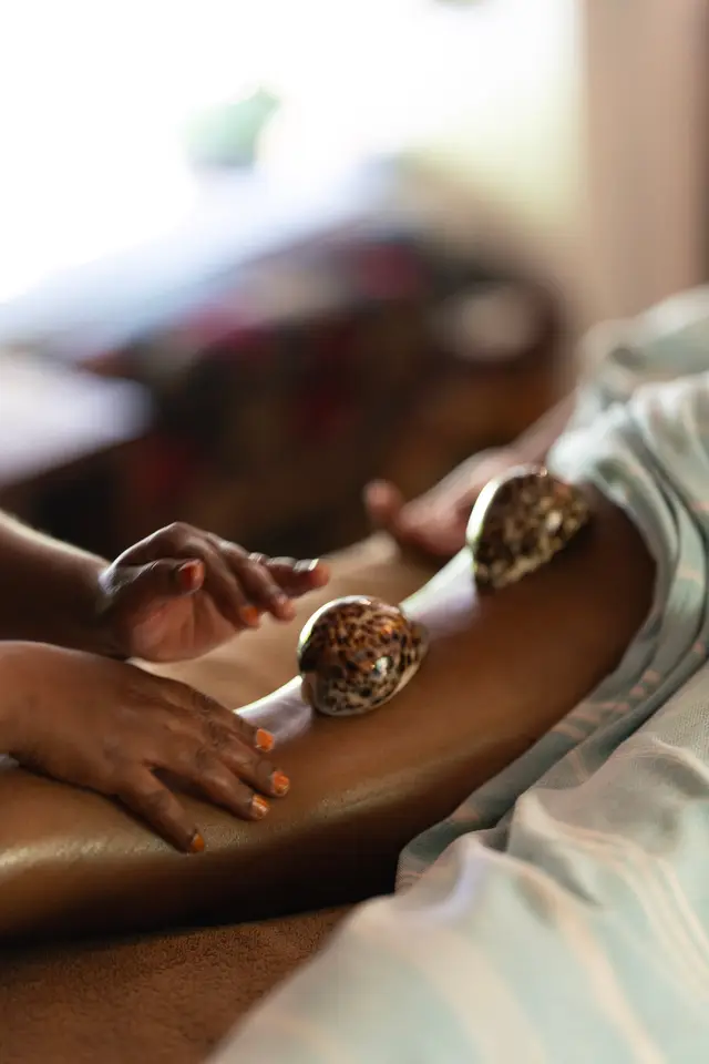 Warm shells being used to massage a guest’s leg during a spa treatment