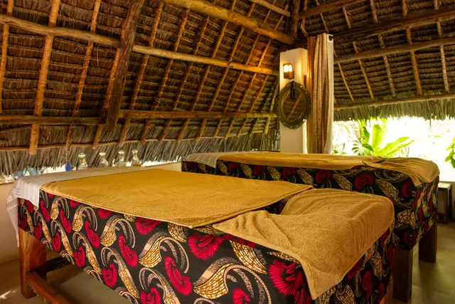 Treatment beds covered in colourful African print cloth in a thatched treatment room
